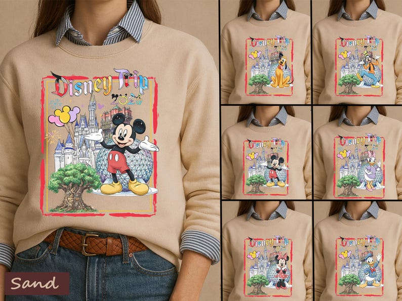 May include: A sand-colored crewneck sweatshirt featuring a graphic print with the text Disney Trip. The design includes a castle, a large tree, and various Disney characters like Mickey Mouse, Pluto, Goofy, Daisy Duck, Minnie Mouse, and Donald Duck.