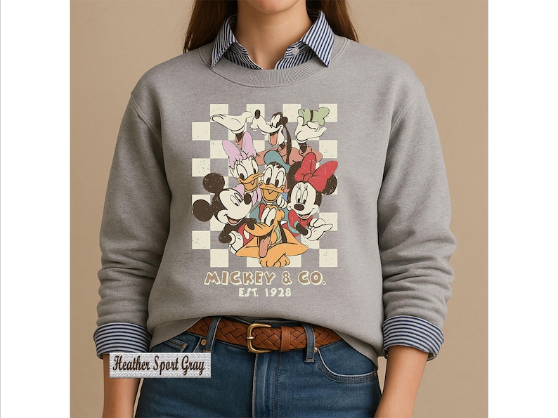 May include: A heather sport gray crewneck sweatshirt featuring a graphic of Mickey Mouse, Minnie Mouse, Donald Duck, Daisy Duck, Goofy, and Pluto over a cream and white checkered background. The text reads MICKEY & CO. EST. 1928 in a brown font.