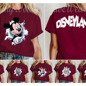 May include: A maroon short-sleeve t-shirt featuring a graphic of Mickey Mouse emerging from a white torn paper effect on the front and the word DISNEYLAND in large white letters on the back, with additional variations showing other characters.