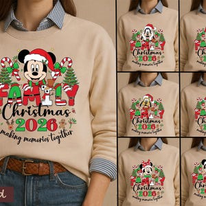 May include: A sand-colored crewneck sweatshirt featuring a graphic of Mickey Mouse in a Santa hat, surrounded by Christmas trees, candy canes, and the text "FAMILY Christmas 2026 making memories together" in red, green, and black ink.
