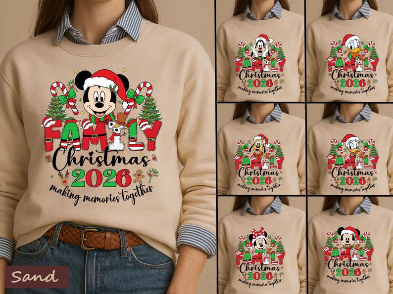 May include: A sand-colored crewneck sweatshirt featuring a graphic of Mickey Mouse in a Santa hat, surrounded by Christmas trees, candy canes, and the text "FAMILY Christmas 2026 making memories together" in red, green, and black ink.