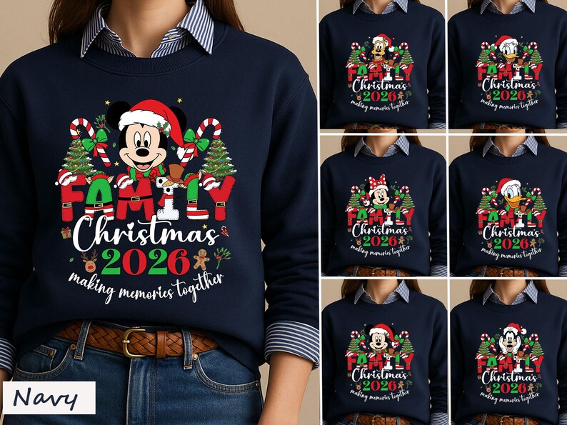 May include: A navy blue crewneck sweatshirt featuring a graphic print of Mickey Mouse in a Santa hat, surrounded by Christmas trees, candy canes, and the text "FAMILY Christmas 2026 making memories together" in red, white, and green colors.