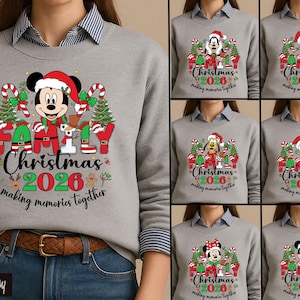 May include: A sport gray crewneck sweatshirt featuring a graphic print of Disney characters wearing Santa hats, surrounded by Christmas trees and candy canes. The text reads Family Christmas 2026 making memories together in red, green, and black.
