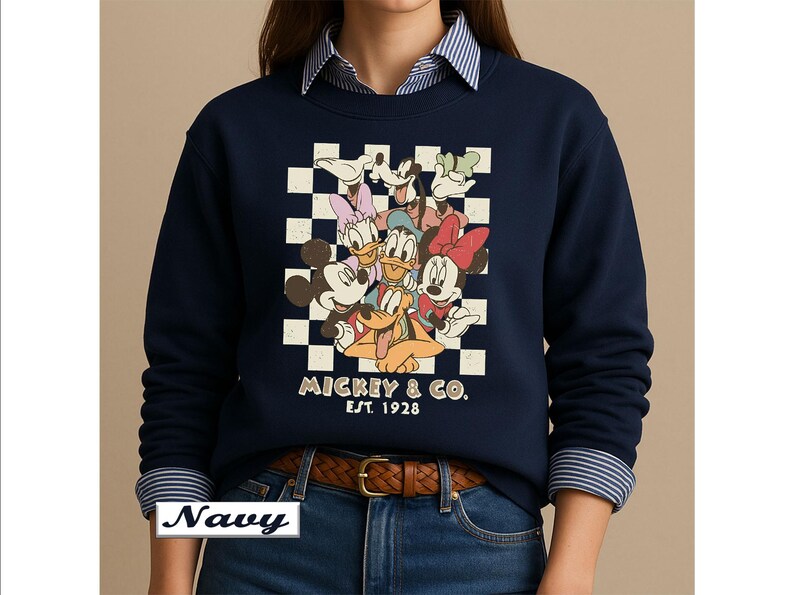 May include: A navy blue crewneck sweatshirt featuring a graphic print of Mickey Mouse, Minnie Mouse, Donald Duck, Daisy Duck, Goofy, and Pluto over a white and navy checkered background with the text MICKEY & CO. EST. 1928 printed below the characters.