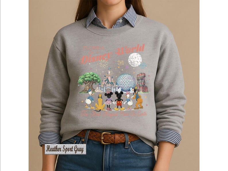 May include: A heather sport gray crewneck sweatshirt featuring a graphic of Disney characters including Mickey Mouse, Minnie Mouse, Donald Duck, Daisy Duck, Pluto, and Goofy standing before park landmarks with the text Disney World and The Most Magical Place On Earth.