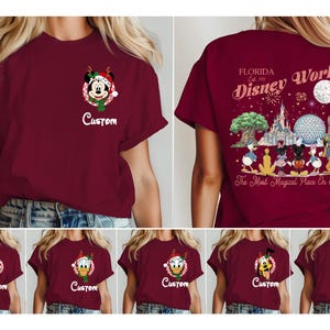 May include: A maroon t-shirt featuring a small graphic on the front left chest of a character in a Christmas hat inside a circle with the word Custom below it. The back displays a Disney World Florida graphic with characters and fireworks.