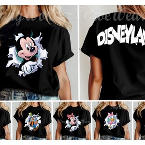 May include: A black short-sleeve t-shirt featuring a graphic of Mickey Mouse emerging from a white torn paper effect on the front and the word Disneyland printed in large white letters across the back, with additional character options shown below.
