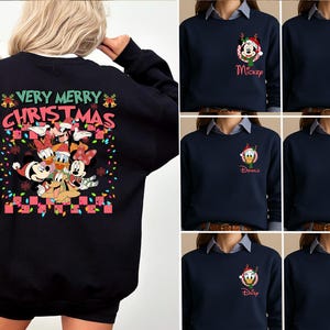 May include: A black long-sleeve sweatshirt featuring a large back graphic of Disney characters in Santa hats with the text "VERY MERRY CHRISTMAS" and colorful lights. The front left chest displays a smaller circular character graphic with a name.