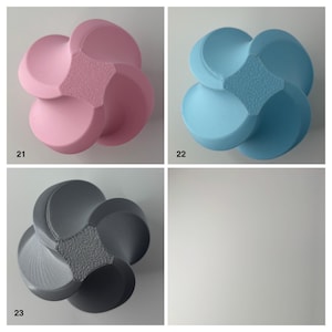 K&ouml;nnte beinhalten: Drei dekorative, abstrakte Objekte in Blumenform in Rosa, Blau und Grau. Jedes hat eine strukturierte Mitte und abgerundete Bl&uuml;tenbl&auml;tter. Die Objekte werden vor einem wei&szlig;en Hintergrund mit den Zahlen 21, 22 und 23 angezeigt.