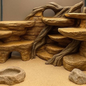 Può includere: Decorazione per habitat di rettili nei toni del marrone e beige, che imita una formazione rocciosa naturale. Presenta più piattaforme, una grotta e una ciotola per l'acqua. È inclusa anche una piccola roccia, creando un ambiente naturale.
