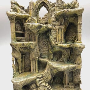 Könnte beinhalten: Ein beigefarbenes und grünes Aquarium-Ornament aus Kunstharz, das eine mehrstöckige architektonische Ruine mit Torbögen, steinartigen Säulen, strukturierten Felsformationen und verschiedenen Ebenen in verwitterter Optik darstellt.