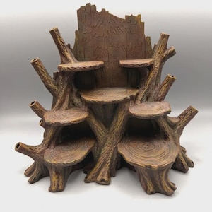 May include: A brown, tree-stump-shaped display stand featuring multiple circular, flat platforms arranged at varying heights. The structure mimics the texture of bark and wood grain, with several protruding branch-like elements extending outward.