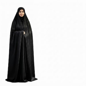 Puede incluir: Una mujer con un abaya negro, una prenda larga y fluida. El abaya tiene un sutil estampado floral y un velo a juego. El fondo es blanco liso.