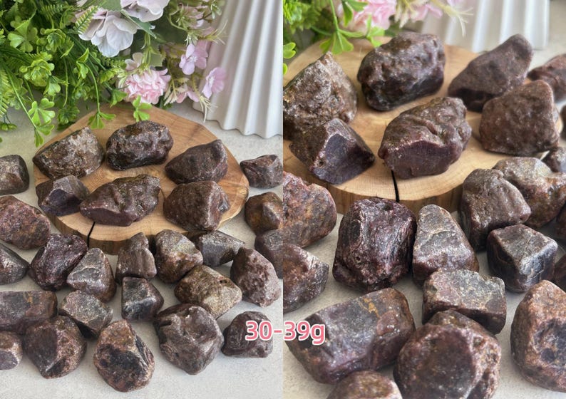 Peut inclure: Une collection de pierres de grenat brutes, brun rouge&acirc;tre fonc&eacute;, aux surfaces irr&eacute;guli&egrave;res et facett&eacute;es. Les pierres varient en taille, certaines pi&egrave;ces &eacute;tant &eacute;tiquet&eacute;es 30-39g. Chaque pierre pr&eacute;sente une teinte terreuse profonde et une texture naturelle brute.
