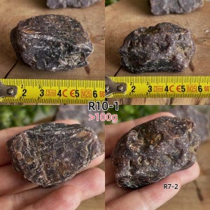 Peut inclure: Un sp&eacute;cimen min&eacute;ral de couleur violet fonc&eacute; &agrave; la texture rugueuse, pr&eacute;sent&eacute; sous quatre angles. Deux images montrent la pierre &agrave; c&ocirc;t&eacute; d'un m&egrave;tre ruban jaune, indiquant une longueur d'environ 6,5 cm. Le texte R10-1, >100g et R7-2 est visible.