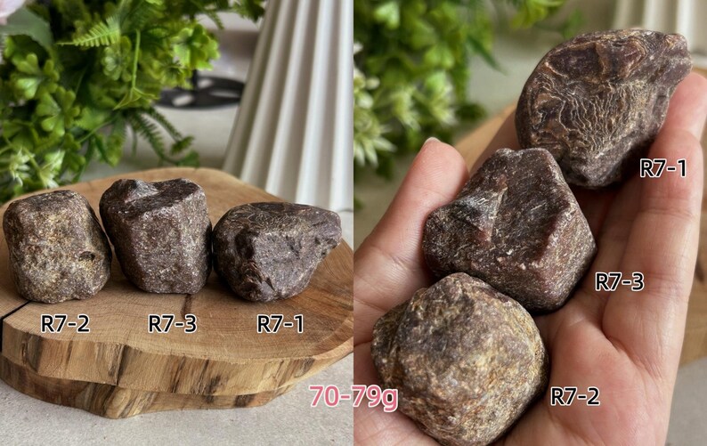 Peut inclure: Trois pierres brutes, brun fonc&eacute;, de forme irr&eacute;guli&egrave;re, &eacute;tiquet&eacute;es R7-1, R7-2 et R7-3. Les pierres ont une surface textur&eacute;e et cristalline et p&egrave;sent entre 70 et 79g. Elles sont pr&eacute;sent&eacute;es sur une tranche de bois et dans une paume.