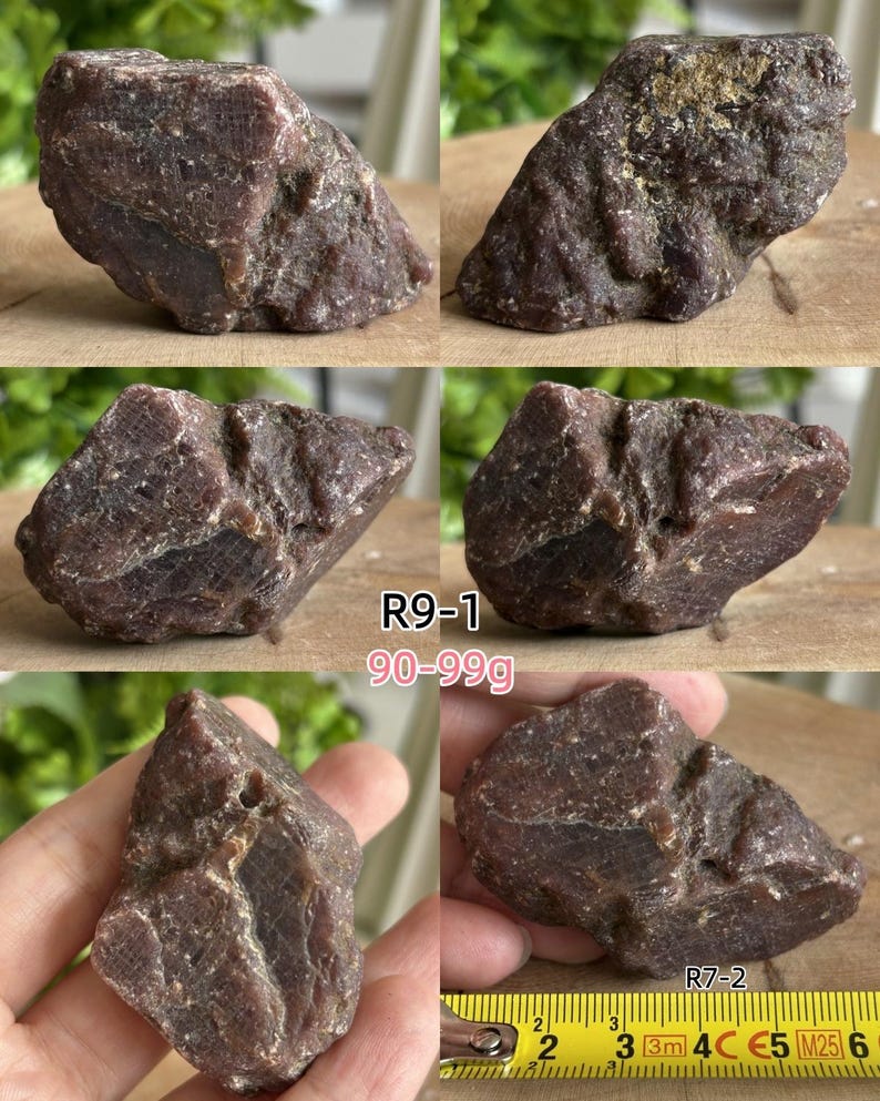 Peut inclure: Un sp&eacute;cimen min&eacute;ral brut brun rouge&acirc;tre fonc&eacute; avec une texture cristalline rugueuse et des facettes irr&eacute;guli&egrave;res. La pierre est &eacute;tiquet&eacute;e R9-1 avec un poids de 90-99g et R7-2, montr&eacute;e &agrave; c&ocirc;t&eacute; d'un m&egrave;tre ruban jaune indiquant plus de 5 centim&egrave;tres.