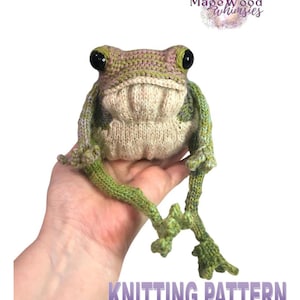 May include: A knitted frog toy with large black eyes, in shades of green, tan, and pink. The frog has long, detailed legs and the text "KNITTING PATTERN" is visible at the bottom. The MageWood Whimsies logo is in the top right corner.
