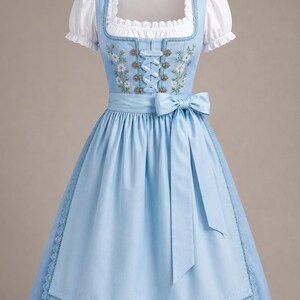 May include: A light blue dirndl dress featuring a white blouse with short puff sleeves, a square neckline, and a bodice with floral embroidery and silver-toned metal hooks for lacing. The skirt includes a matching apron with a tied bow at the waist.