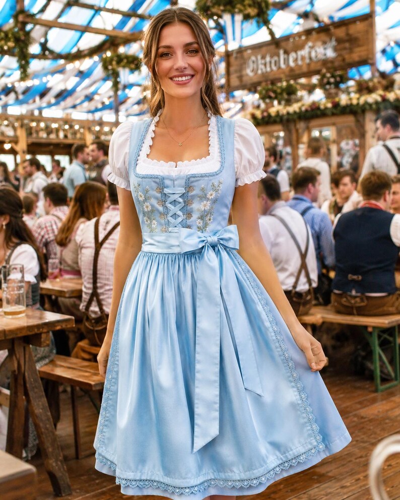May include: A light blue dirndl dress featuring a white puff-sleeve blouse, a square neckline, and a bodice with floral embroidery and lace-up detailing. The skirt includes a matching satin ribbon waist tie and a delicate lace trim at the hem.