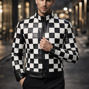 Puede incluir: Chaqueta de cuero a cuadros blancos y negros con cuello alzado y cremallera frontal. La chaqueta se lleva sobre una camisa negra y se combina con pantalones negros. Se ve un reloj en la muñeca.