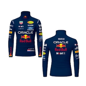 May include: Navy blue long-sleeved turtleneck shirt featuring the Red Bull Racing logo and sponsor logos. The front displays the Oracle and Red Bull logos, with the text "MAX" and a flag. The back also shows the Red Bull logo and sponsor logos.
