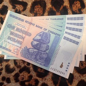May include: A collection of Zimbabwean one hundred trillion dollar banknotes, fanned out on a leopard print background. The notes are predominantly blue, pink, and green, with the text "ONE HUNDRED TRILLION DOLLARS". The design includes a rock formation.