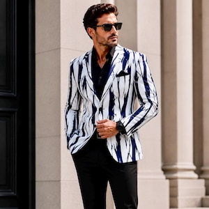 Könnte beinhalten: Ein weißer Blazer mit einem vertikalen Streifenmuster in Marineblau. Der Blazer wird über einem schwarzen Hemd getragen und mit einer schwarzen Hose kombiniert. Die Person trägt eine Sonnenbrille und eine schwarze Uhr.