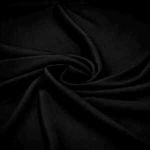 May include: A solid black fabric with a smooth, matte texture, arranged in a series of soft, flowing folds and deep, curved drapes that create a sense of depth and movement across the surface of the material, highlighting its consistent dark tone.
