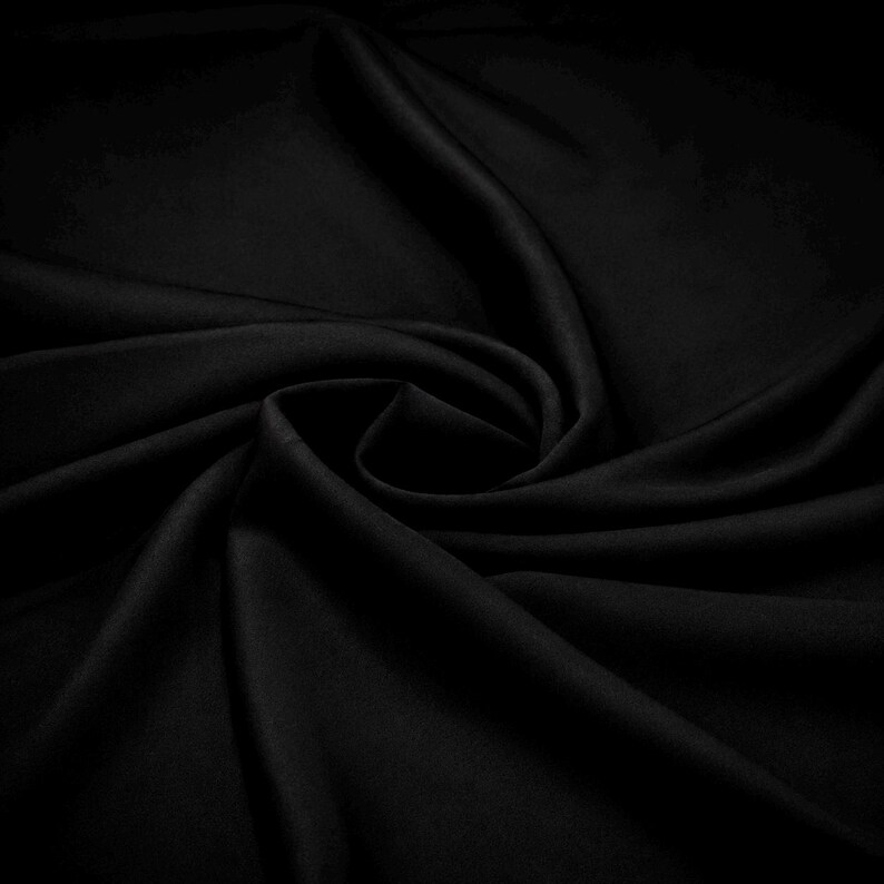 May include: A solid black fabric with a smooth, matte texture, arranged in a series of soft, flowing folds and deep, curved drapes that create a sense of depth and movement across the surface of the material, highlighting its consistent dark tone.