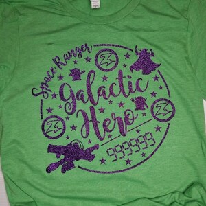 May include: Green t-shirt with a purple glitter design of a circle with the text "Space Ranger Galactic Hero" and stars, a spaceship, a lightning bolt, and a robot.