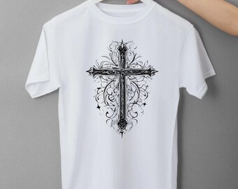 May include: White t-shirt featuring a detailed black cross design with ornate floral and scrollwork. The cross is centered on the shirt, with the design extending outwards. The shirt is hanging on a white hanger against a gray background.