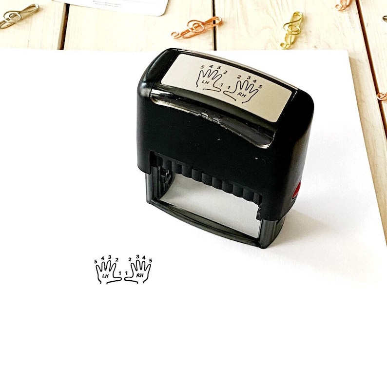 May include: Black self-inking stamp with a white rectangular plate. The plate has a graphic of two hands with numbered fingers. The text on the plate reads "5 4 3 2 1 LH 1 2 3 4 5 RH".