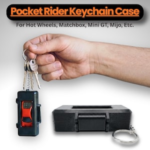 Puede incluir: Estuche negro para llavero con un coche de juguete rojo en el interior, sujeto por un llavero con llaves. El texto "Pocket Rider Keychain Case" se muestra encima del estuche. El texto "For Hot Wheels, Matchbox, Mini GT, Mijo, Etc." se muestra debajo.
