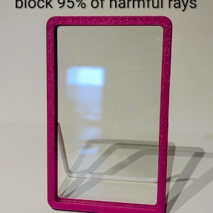 May include: A rectangular, magenta-colored frame with rounded corners, holding a clear acrylic panel. The text at the top reads "UV resistant acrylic panels block 95% of harmful rays."