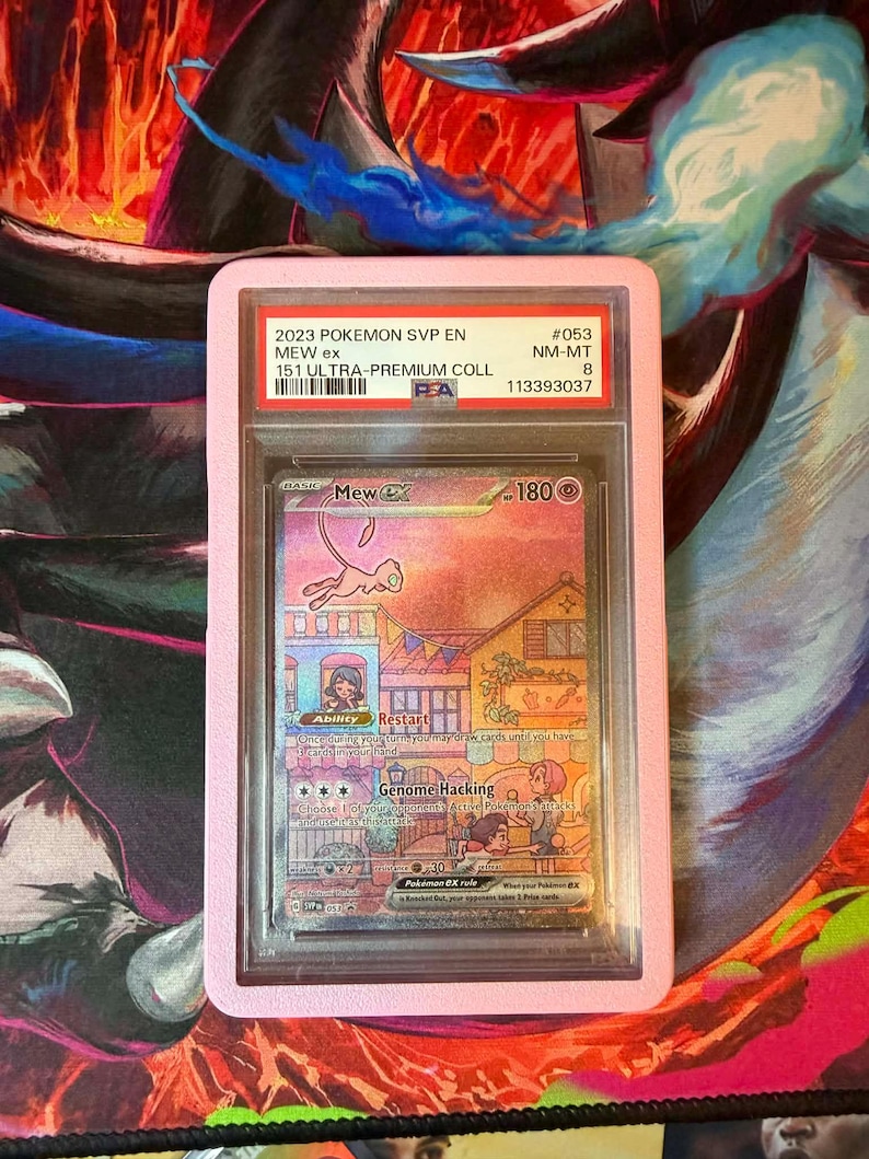 May include: A graded Pok&eacute;mon card featuring Mew ex, encased in a pink holder. The card displays colorful artwork of a town scene with the text "Genome Hacking" and "Restart". The holder has text indicating it's from the 2023 Pok&eacute;mon SVP EN 151 Ultra-Premium collection.