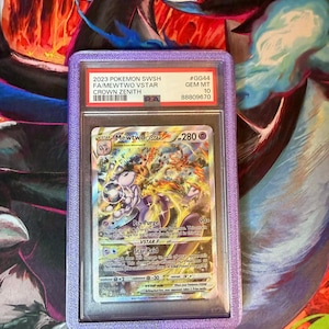 May include: A graded Pok&eacute;mon card featuring Mewtwo VSTAR from the Crown Zenith set. The card is encased in a purple holder with text that reads "2023 Pokemon SWSH FA/Mewtwo VSTAR Crown Zenith". The card has a Gem Mint 10 grade.