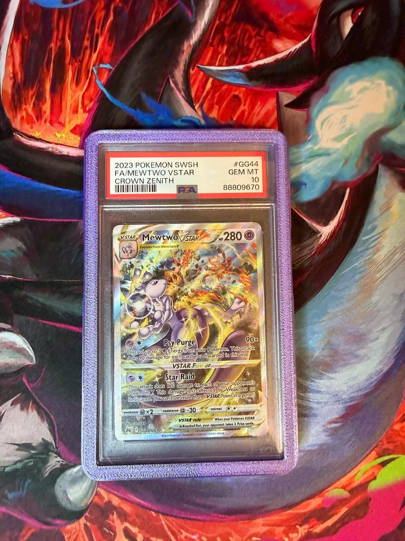 May include: A graded Pok&eacute;mon card featuring Mewtwo VSTAR from the Crown Zenith set. The card is encased in a purple holder with text that reads "2023 Pokemon SWSH FA/Mewtwo VSTAR Crown Zenith". The card has a Gem Mint 10 grade.