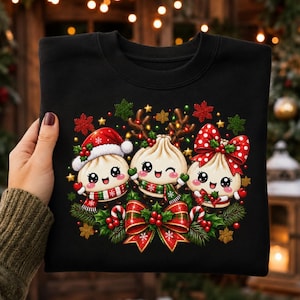 May include: A black crewneck sweatshirt featuring a graphic of three smiling, anthropomorphic dumplings. The left dumpling wears a Santa hat and scarf, the centre has reindeer antlers, and the right wears a red polka-dot bow, all amidst holly.