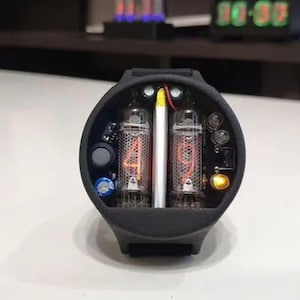 May include: A white ceramic mug with a black handle and the text "But First, Coffee" in a black, bold font. The mug is on a white surface. The mug is approximately 4 inches tall.