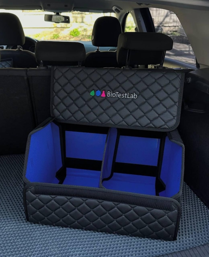 May include: Black quilted car organizer with blue interior compartments. The organizer has a lid and is designed to fit in the trunk of a car. The text "BioTestLab" is visible on the lid.