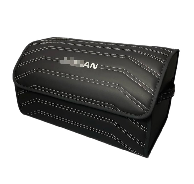 May include: Black storage container with white stitching and the text "AN". The container has a rectangular shape with a curved top and a handle on the side. The stitching creates a geometric pattern.