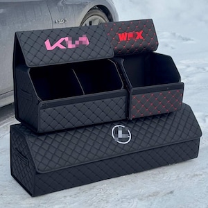 Puede incluir: Organizadores de maletero de coche acolchados negros con detalles de texto rosa y rojo. Los organizadores est&aacute;n apilados, con m&uacute;ltiples compartimentos y un logotipo. El dise&ntilde;o incluye un patr&oacute;n de diamantes.