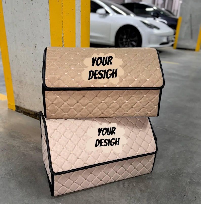 May include: Two beige car storage organizers with a quilted pattern and black trim are stacked on top of each other. Each organizer has a lid and the text "YOUR DESIGN" on the front. The background shows a parking garage with cars.