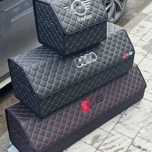 May include: Three black car storage boxes with diamond stitching. The top box has a logo and the name "Payton". The middle box has a logo and the number "6". The bottom box has red stitching.