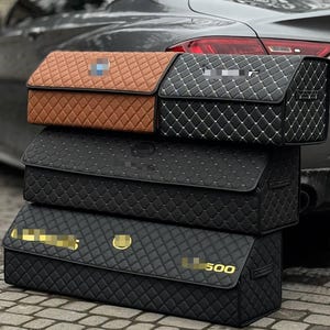 Könnte beinhalten: Vier Auto-Kofferraum-Organizer in verschiedenen Farben, übereinander gestapelt. Der oberste Organizer ist braun, der zweite schwarz mit weißen Nähten, der dritte schwarz und der untere schwarz mit dem Text "LL 500".