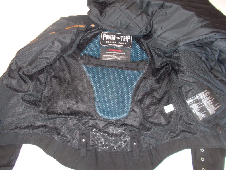 May include: Black motorcycle jacket interior with a blue mesh back protector. The jacket has a quilted hood and the "POWER-TRIP" logo is visible. The interior is made of black mesh and fabric.