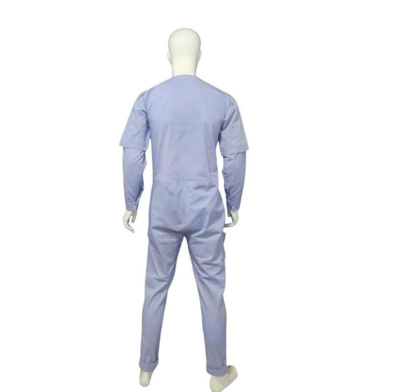 May include: A light blue jumpsuit worn by a white mannequin, shown from the back. The garment features long sleeves, a round neckline, and full-length trousers. The fabric appears smooth and solid in color, covering the torso, arms, and legs.