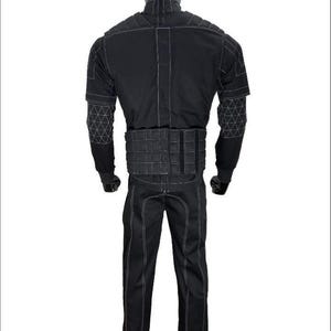 May include: A black tactical suit displayed on a mannequin. The suit features white stitching, a quilted vest, and geometric patterns on the sleeves. The pants have a straight leg design. The mannequin has a black head.