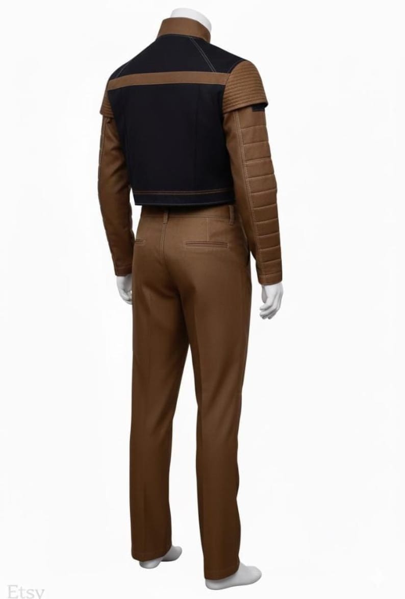 May include: A brown and black costume featuring a cropped jacket with padded shoulders and long sleeves, paired with matching brown trousers. The jacket has a black upper section and brown accents. The outfit is displayed on a mannequin.